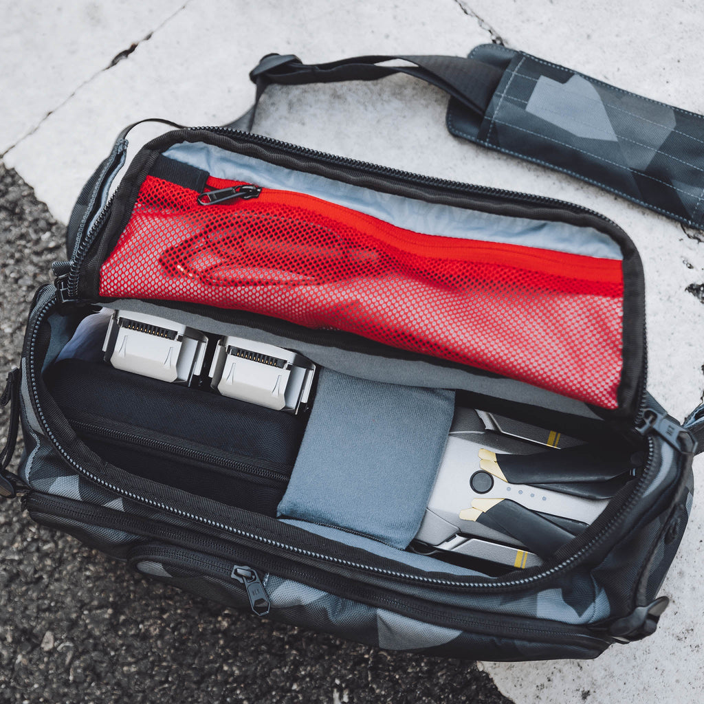 HEX Ranger Glacier Camo DSLR Sling, top view, unzipped to show an assortment of camera gear inside