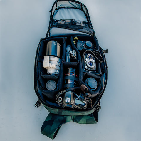 HEX Ranger Clamshell Camo DSLR Backpack, front view, opened to show variety of camera gear stored inside