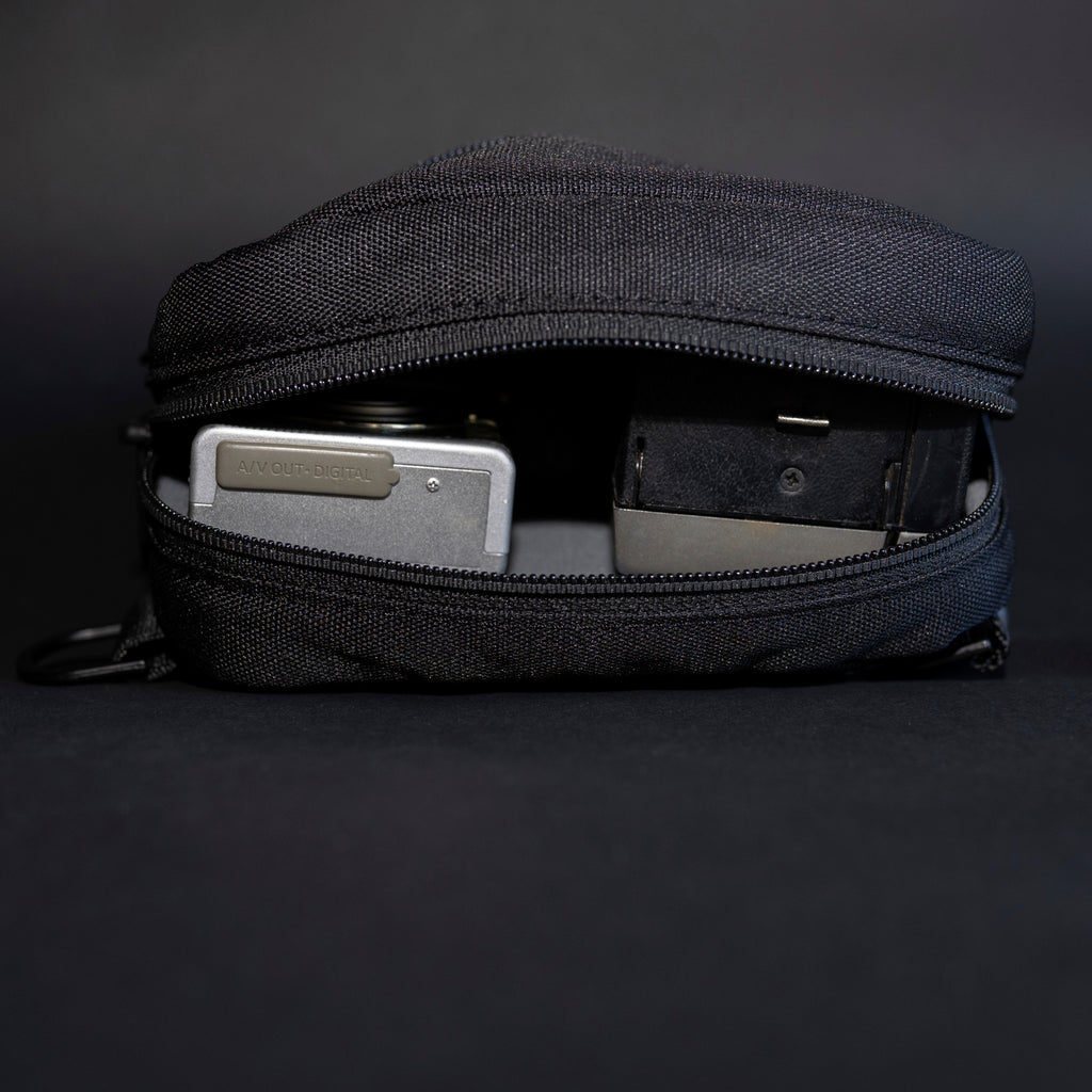 HEX Ranger Camera Crossbody Blackout Camo, shown on its side with a compact camera stored inside.