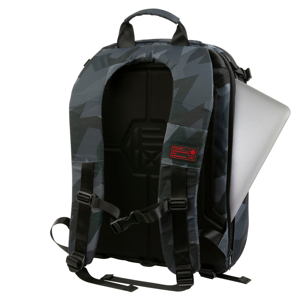 Back view of the Hex Ranger Clamshell Glacier Camo DSLR Backpack with a laptop partially sticking out of the main compartment zipper