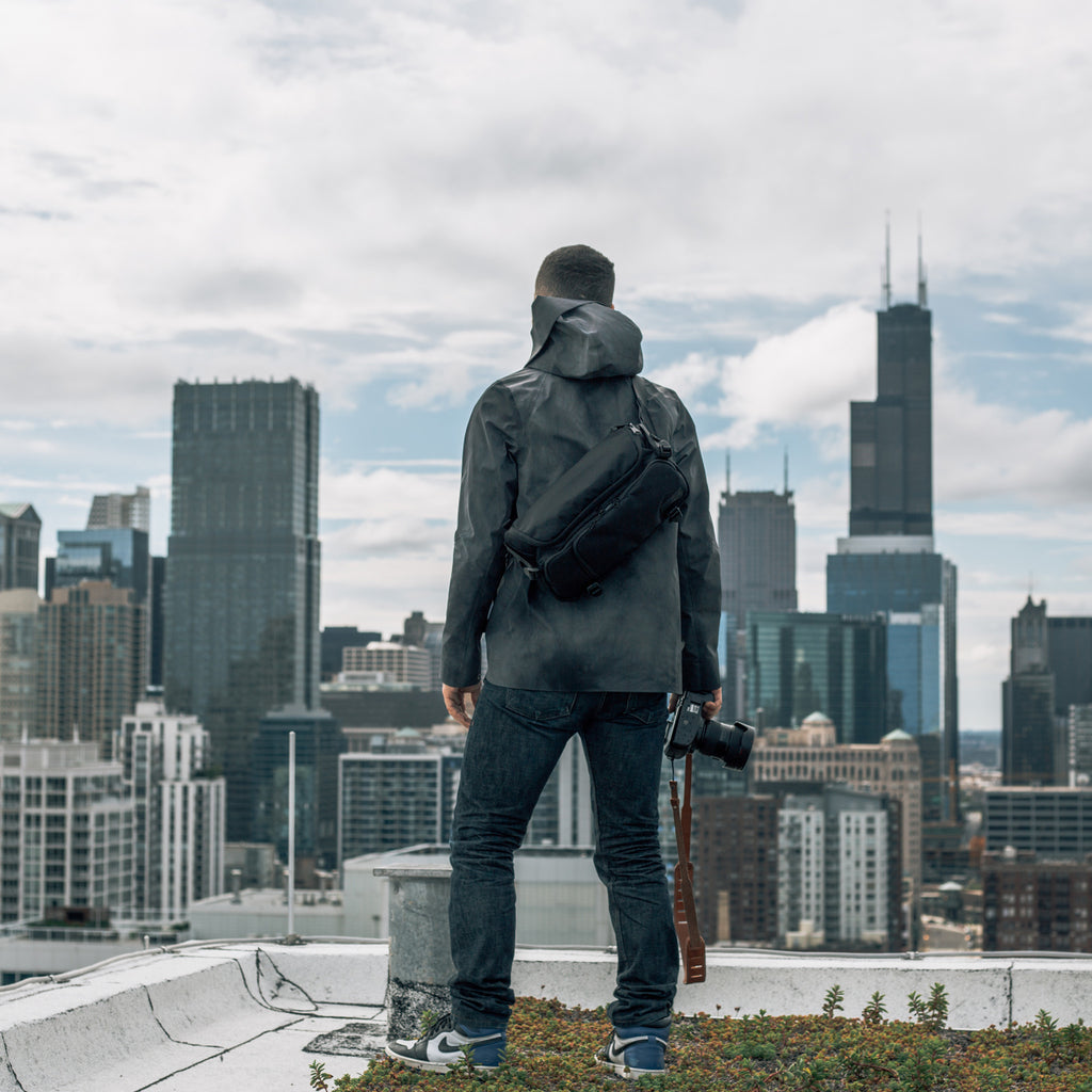Man holding HEX Ranger Black DSLR Sling, looking out at Chicago skyline